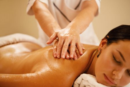 Close-up of woman relaxing during back massage at spa salon.